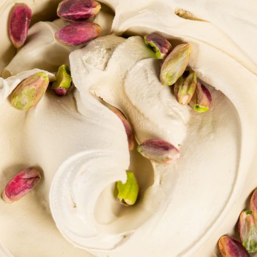 Creamy gelato with smooth, swirled textures, topped with whole and halved pistachios for a rich, nutty garnish.