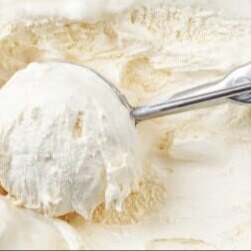 A metal scoop lifts a rounded scoop of vanilla ice cream from a creamy, tub of ice cream.