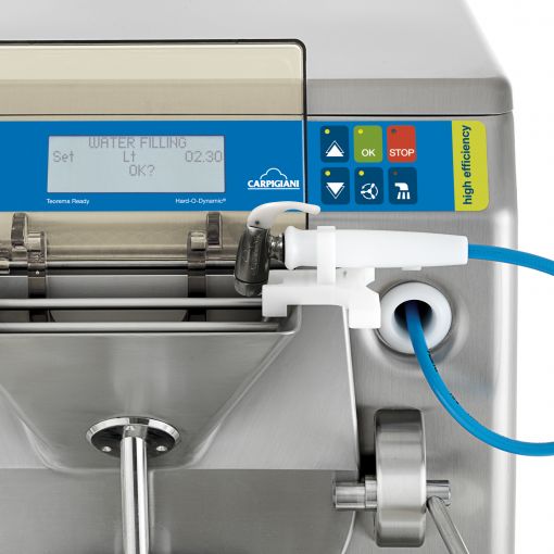 A stainless steel commercial gelato machine with a digital display, control buttons, and a blue hose attached for water filling.