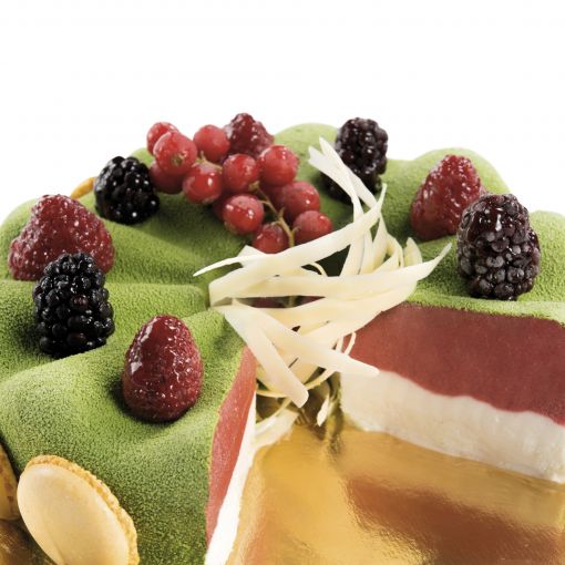 A gourmet layered gelato crystal with a green velvet-like surface, topped with red currants, blackberries, raspberries, and white chocolate shavings.